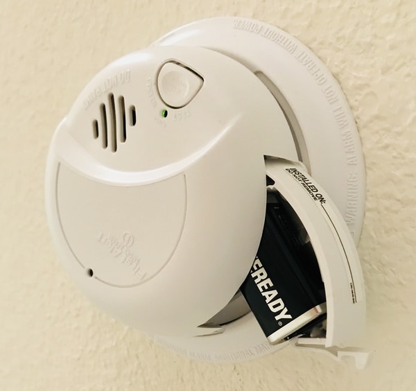 A smoke alarm opened so you can see the battery compartment.