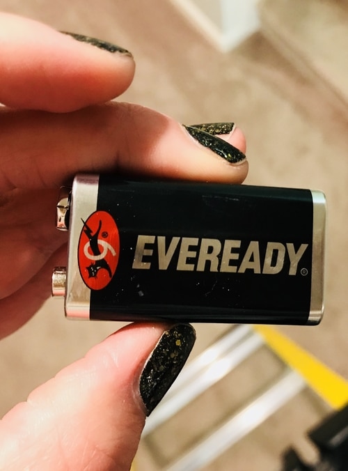 A hand holding a 9-volt battery.