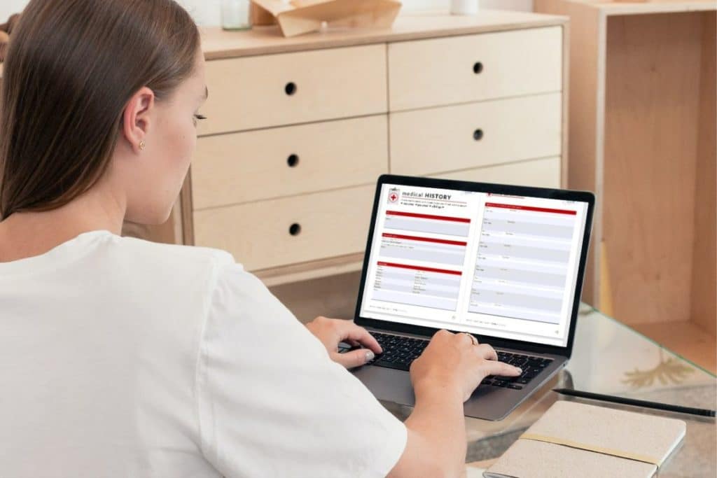 woman entering medical information on a digital document on laptop