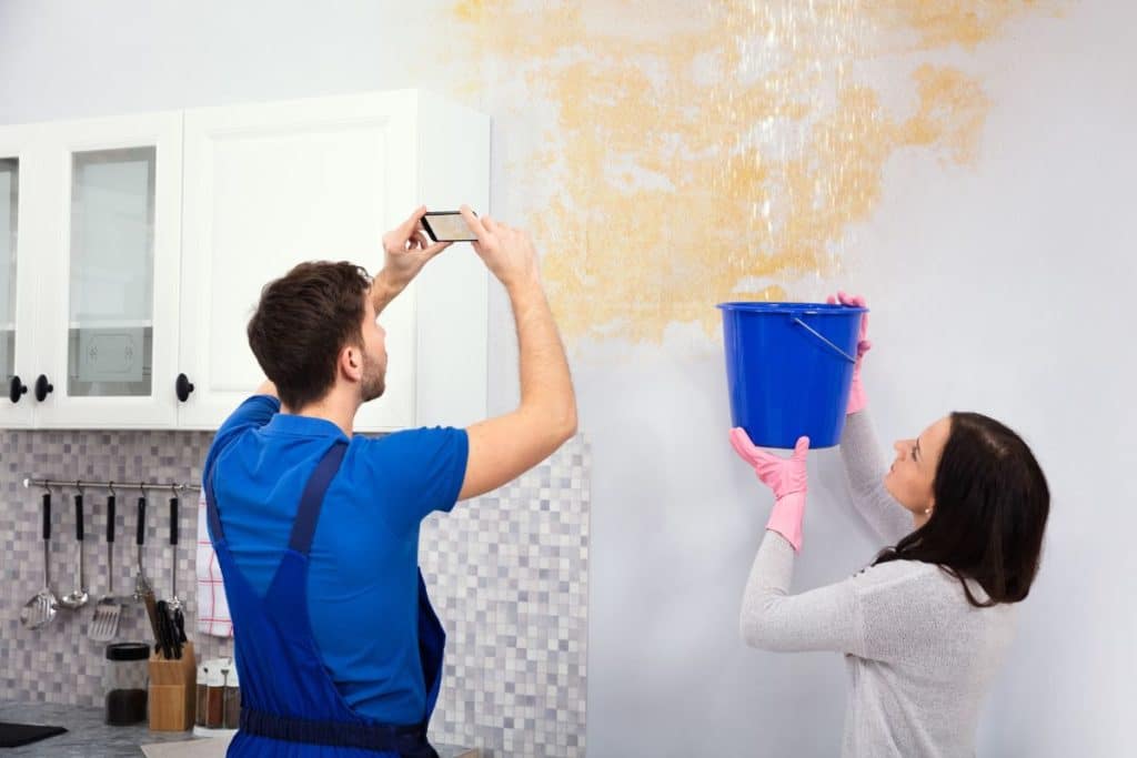 couple thinking about buying homeowners insurance while looking at water dripping from their ceiling