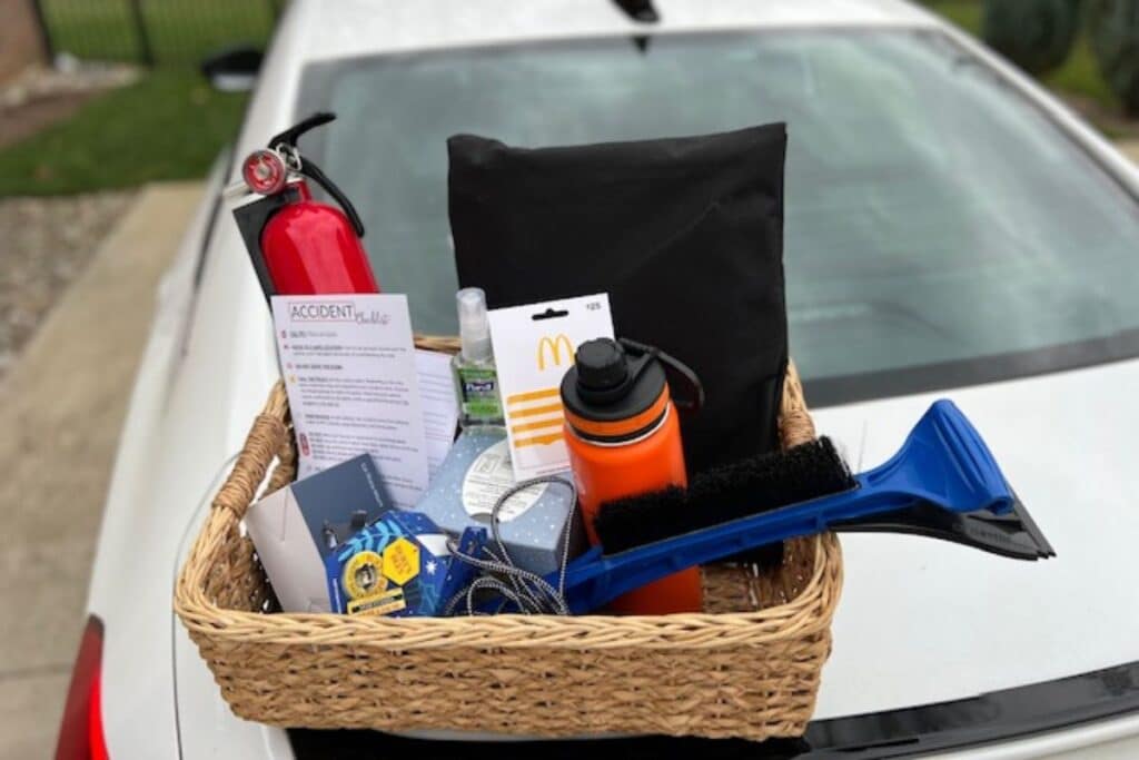 new driver gift basket sititng on trunk of white car.