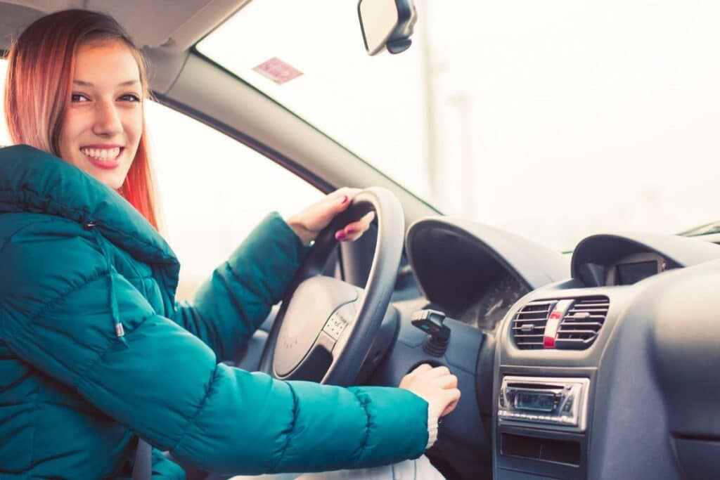 smiling teenage girl starting her car.
