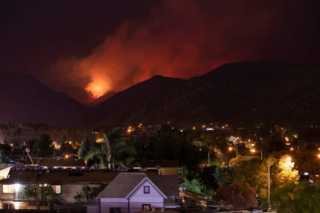 neighborhood at night in front of wildfire in mountains.