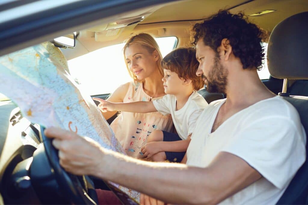 family sitting in car using map from their summer car kit.