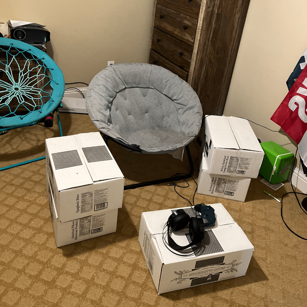 Boxes of food storage on the floor of a teenager's bedroom, holding a gaming station.