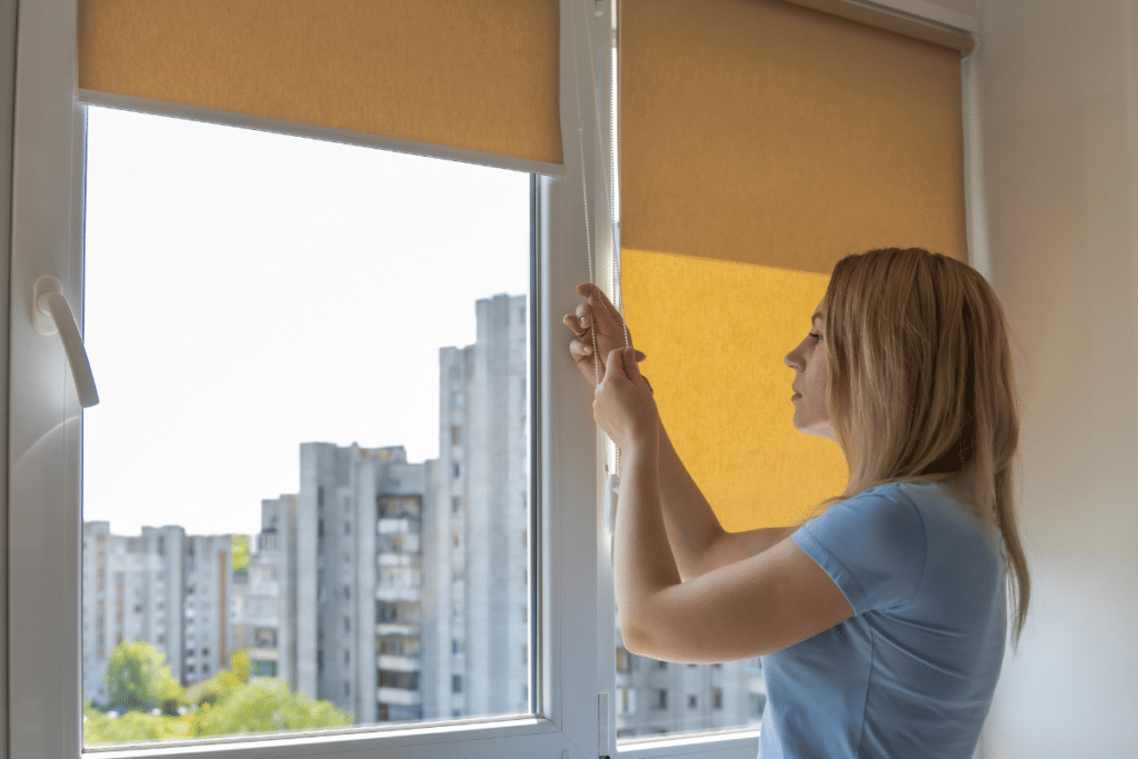 Woman closing blinds on her window.