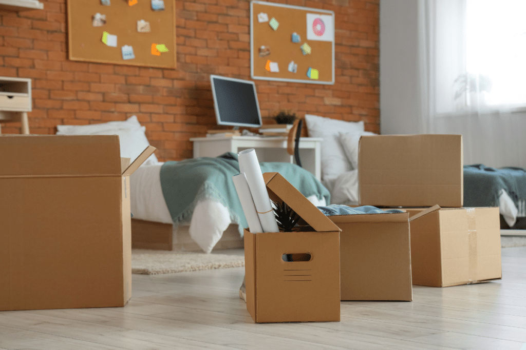 college dorm room full of unpacked boxes.